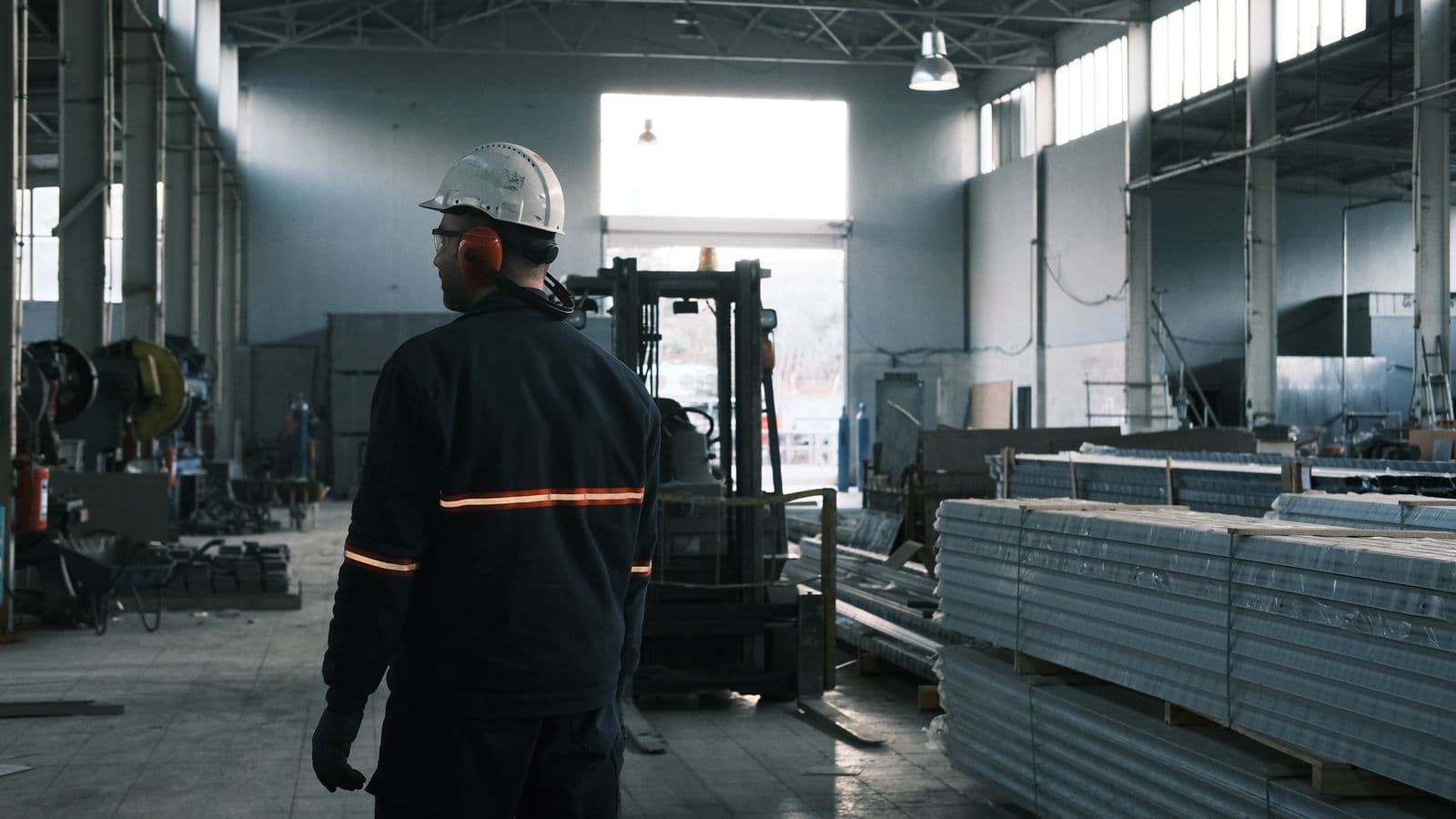 Factory worker overseeing a production floor stacked with metal panels
