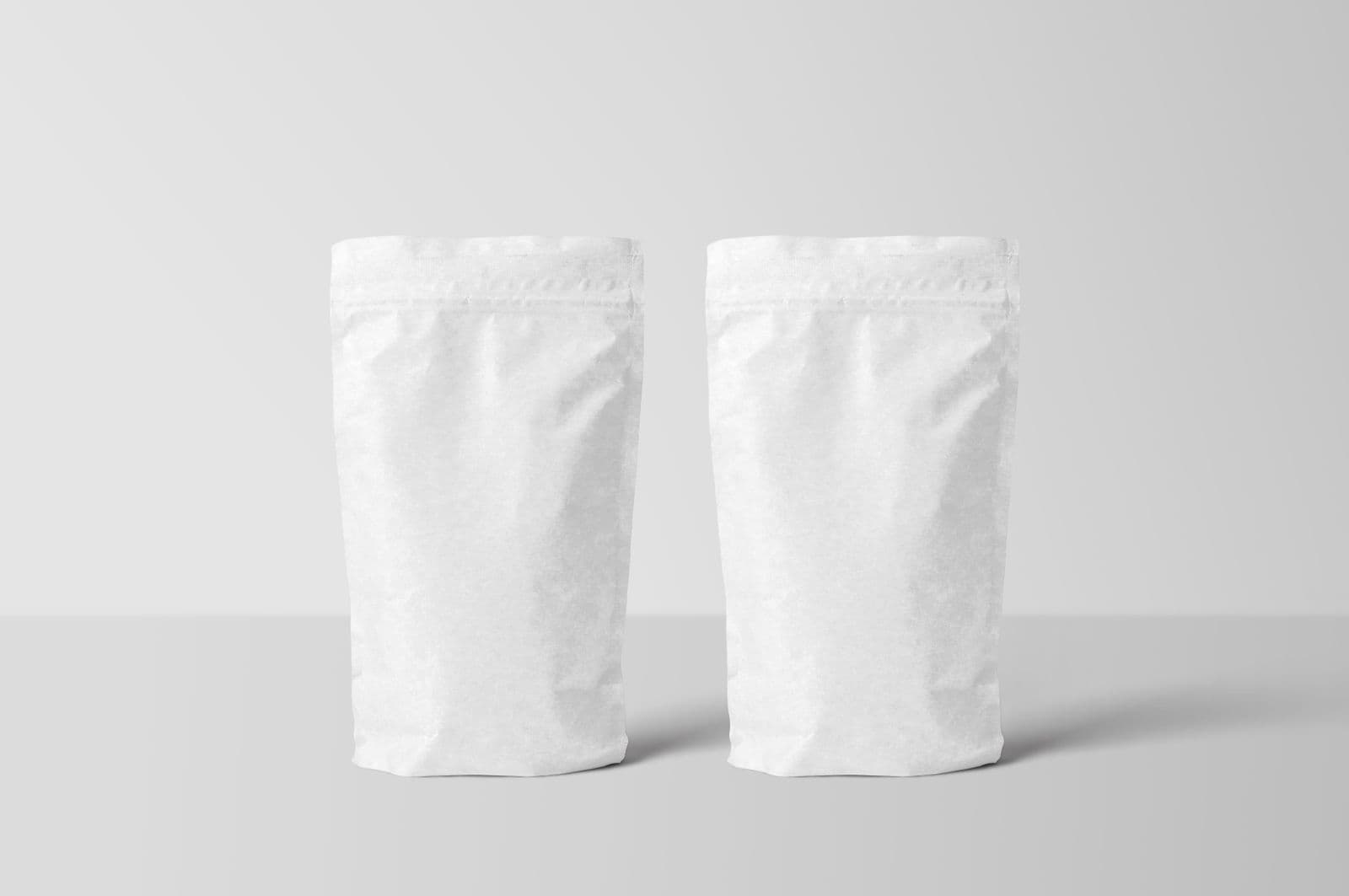 Two blank white stand-up pouches on a plain background