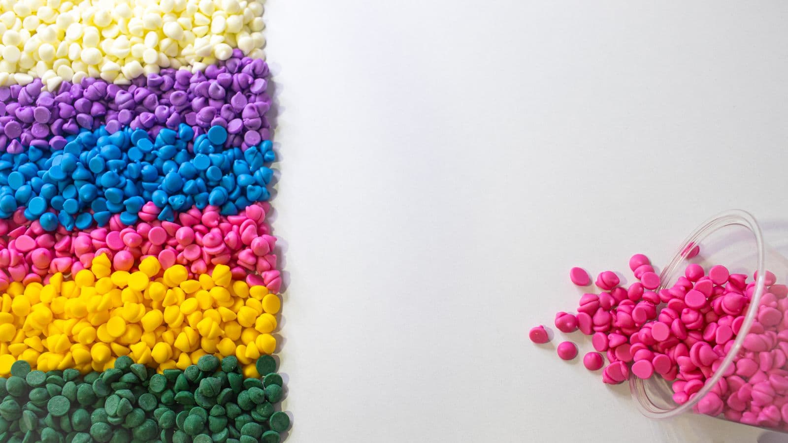 Rows of colorful plastic resin pellets on a white background